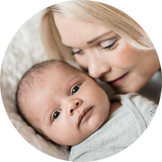 Close-up of a baby lying down, with a woman gently nuzzling the baby, both looking content.